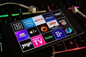 Logos verschiedner Streamingdienste auf dem Bildschirm eines Smartphones auf einer Tastatur